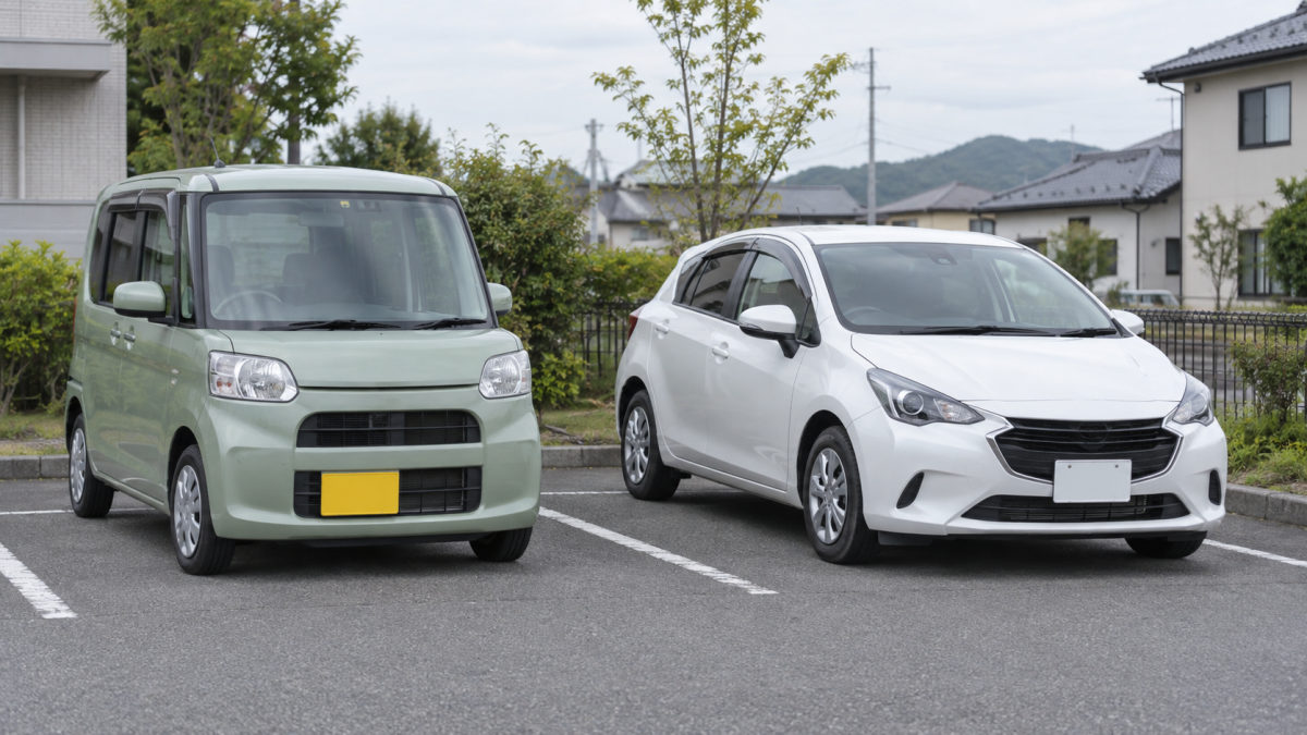 淡绿色軽自動車与白色普通紧凑型车并排停放。